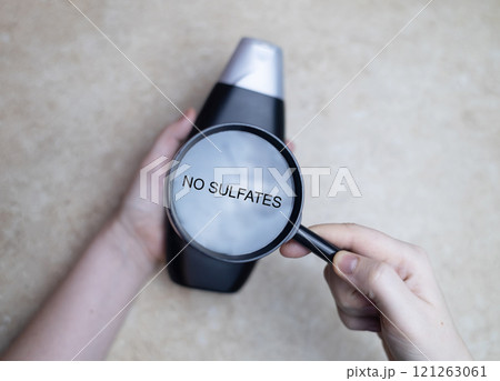 Female hands holding a can of shampoo, where it is written sulfate free, no sulfates. The concept of safe composition of shampoo without aggressive components Female hands holding a can of shampoo, where it is written sulfate free, no sulfates. The concept of safe composition of shampoo without aggressive components 121263061