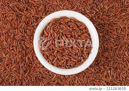 red rice in a ceramic bowl as a background. Top view. Flat lay 121263638