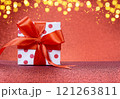 White gift box with polka dots with red bow stands on shiny background. Defocused lights. Christmas, New Year, Saint Valentine, March 8, Mother's Day, birthday. Copy space 121263811
