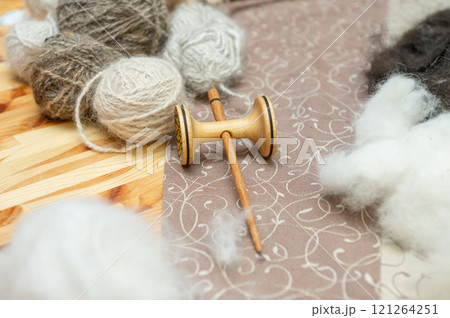 Wooden spinning wheel with yarn balls on patterned fabric Wooden spinning wheel with yarn balls on patterned fabric 121264251