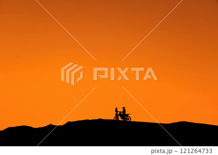 Silhouette of a girl and a man on a motorcycle.  121264733
