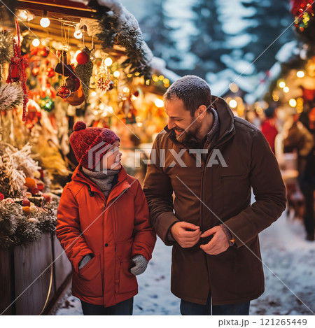 Father and son are enjoying the festive atmosphere of a Christmas market, taking in the sights and sounds of the season 121265449