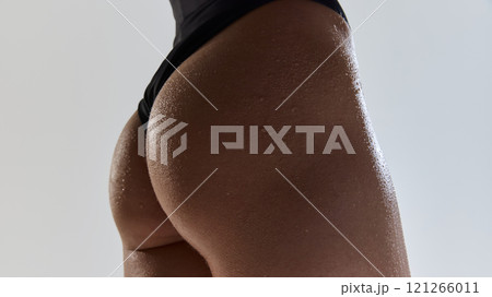 Close up photo of female legs, buttocks against grey studio background. Woman posing in swimwear. Skin texture. Close up photo of female legs, buttocks against grey studio background. Woman posing in swimwear. Skin texture. 121266011