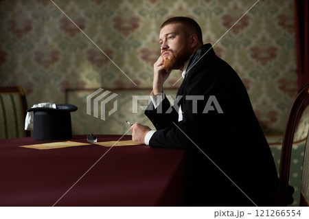Romantic side view portrait of young gentleman in love looking away pensively sitting at table and writing letter with ink, copy space Romantic side view portrait of young gentleman in love looking away pensively sitting at table and writing letter with ink, copy space 121266554