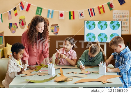 Multiethnic group of children cutting cardboard during art and craft class making dinosaur figures and learning about Earth history copy space 121266599