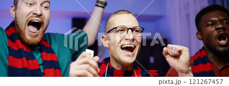 Cropped header image of portrait of excited sports fans cheering and screaming while celebrating win and wearing matching team scarves 121267457