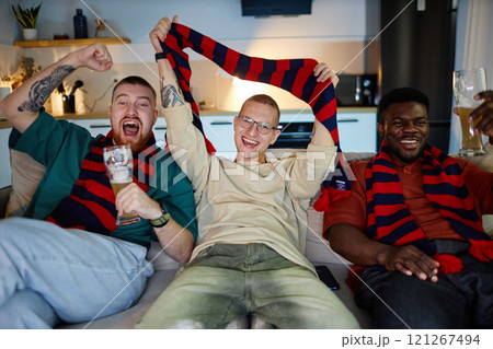 Front view portrait of three adult men watching sports match on TV and cheering with accessories in team colors, copy space Front view portrait of three adult men watching sports match on TV and cheering with accessories in team colors, copy space 121267494