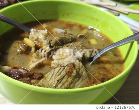 A bowl of hearty Gulai Kambing, a rich Indonesian soup brimming with tender goat meat, vegetables, and spices. 121267676
