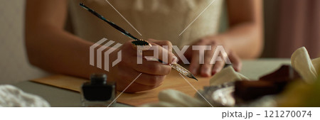 Header closeup of classic young lady writing letter with focus on female hands holding intricate ink pen and ornate ring, copy space Header closeup of classic young lady writing letter with focus on female hands holding intricate ink pen and ornate ring, copy space 121270074