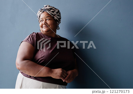 Minimal waist up portrait of authentic senior African American woman wearing headscarf and looking way on blue background with soft natural daylight, copy space 121270173