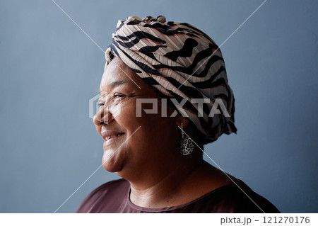 Minimal side view portrait of senior African American woman smiling kindly with soft natural light on blue background in studio and wearing traditional headscarf Minimal side view portrait of senior African American woman smiling kindly with soft natural light on blue background in studio and wearing traditional headscarf 121270176