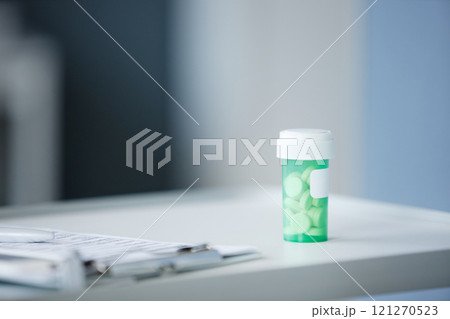Close up background image of green bottle with prescription pills on white desk in clinical , copy space 121270523
