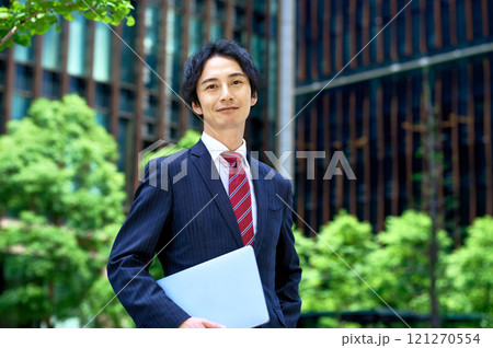オフィスビルのでパソコンを持って立つビジネスマン 121270554