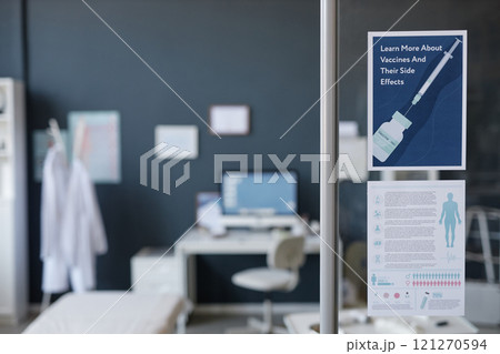 Minimal background image of medical clinic interior with focus on vaccine information poster on glass wall, computer desk in blurred background, copy space 121270594