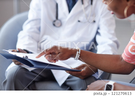 Close up of female hand pointing at clipboard asking questions to doctor during consultation in clinic, copy space Close up of female hand pointing at clipboard asking questions to doctor during consultation in clinic, copy space 121270613