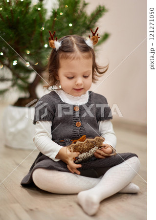 Cute little child girl with wooden snowflakes against the backdrop of Christmas tree 121271050