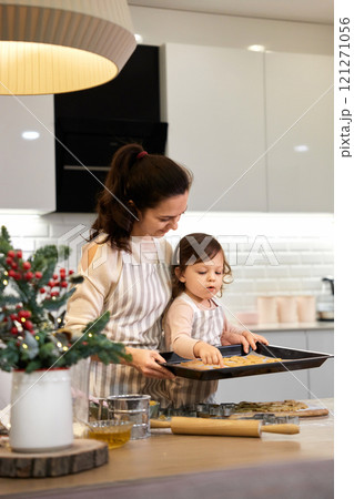 happy mother and little child daughter holding tray with gingerbread cookies in kitchen. Christmas time 121271056