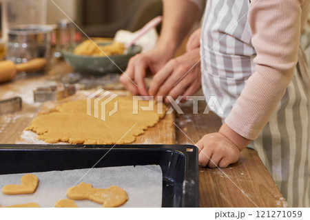close up of mother and little child daughter cutting cookies of raw gingerbread dough in kitchen. close up of mother and little child daughter cutting cookies of raw gingerbread dough in kitchen. 121271059