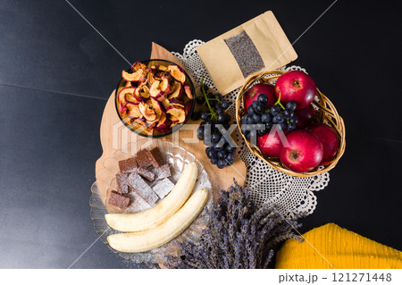 Assortment of fruits, sweets, and dried lavender on a dark background. 121271448