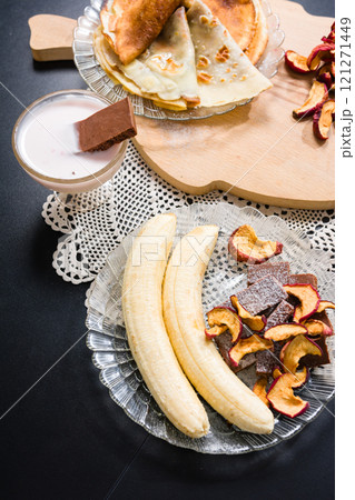 Pancakes, bananas, dried fruit, dessert, and a milkshake on a table. 121271449
