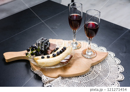 Romantic setup with wine, fruit, and dessert on a wooden board. Romantic setup with wine, fruit, and dessert on a wooden board. 121271454