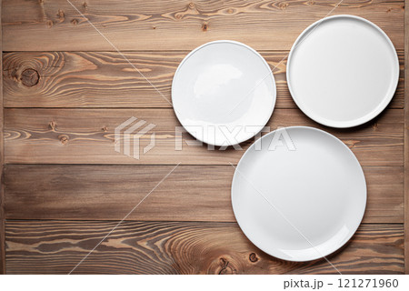 Three empty white plates on wooden table background Three empty white plates on wooden table background 121271960