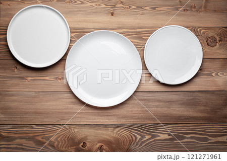 Three empty white plates on wooden table background 121271961