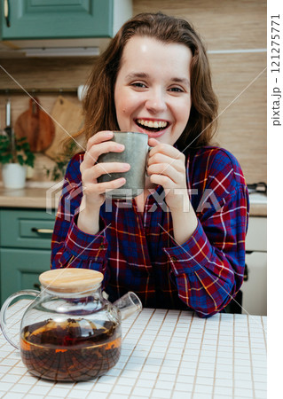 cheerful woman enjoying cup of coffee or tea. lovely lady is sitting at kitchen table and smiling 121275771