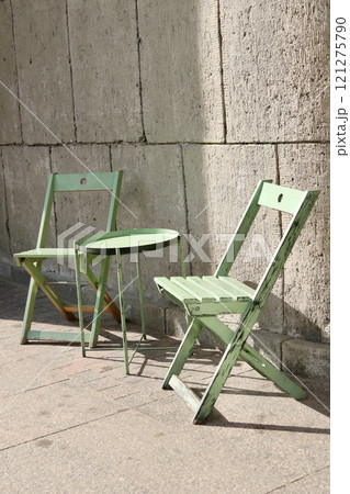 outdoor cafe, green table and chair on background of stone wall. tourist spot for breakfast, lunch. 121275790