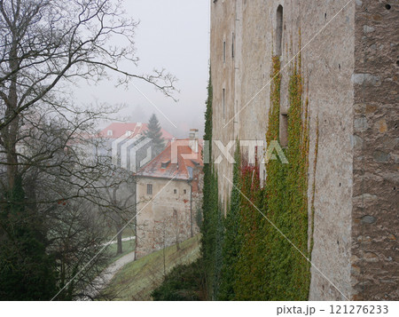 A park area of a Cesky Krumlov Castle in a foggy gloomy smog winter weather A park area of a Cesky Krumlov Castle in a foggy gloomy smog winter weather 121276233