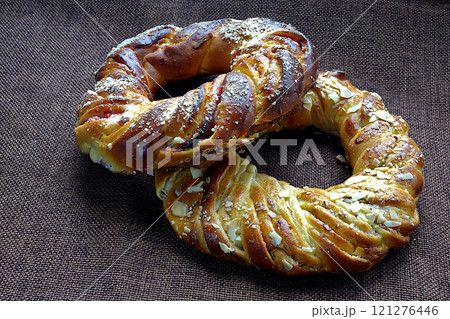 Baking two bagels on a brown cloth. Sweet food multiple ring stuffed and scattered on the surface 121276446