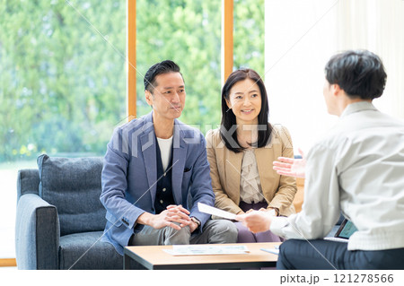 リフォームの打ち合わせをする営業マンとミドル夫婦 リフォームの打ち合わせをする営業マンとミドル夫婦 121278566