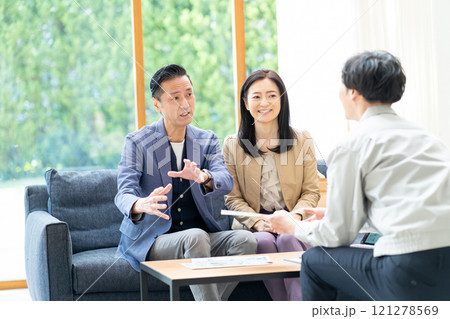 リフォームの打ち合わせをする営業マンとミドル夫婦 121278569