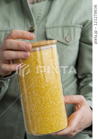 Woman holding Raw corn porridge in sustainable natural packaging. Refillable glass jar. Gluten free cereals. Health gut benefits. Concept of alternative whole spelt grain ingredient. Vegetarian diet 121278636