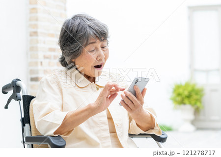 スマホを操作する車椅子のシニア女性 121278717