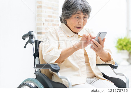 スマートフォンを操作する車椅子のシニア女性 121278726