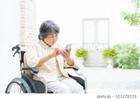 スマートフォンを操作する車椅子のシニア女性 スマートフォンを操作する車椅子のシニア女性 121278729