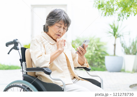 スマートフォンを操作する車椅子のシニア女性 スマートフォンを操作する車椅子のシニア女性 121278730