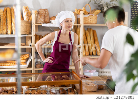Young woman seller helps man buyer choose pastries Young woman seller helps man buyer choose pastries 121279803