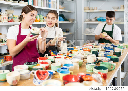Two young women examining pottery in workshop Two young women examining pottery in workshop 121280052