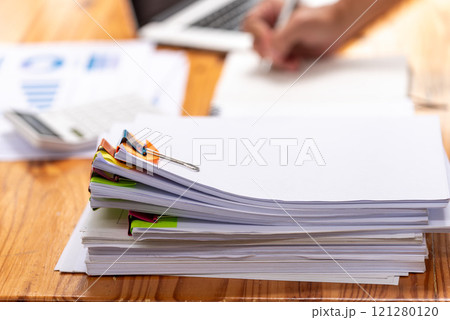 Paper documents are stacked on wooden desks at the workplace. 121280120
