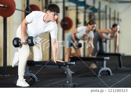 Young guy training with dumbbells on bench Young guy training with dumbbells on bench 121280323