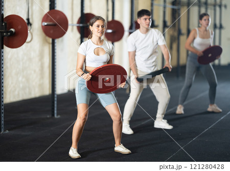 Young woman training with weight plate 121280428