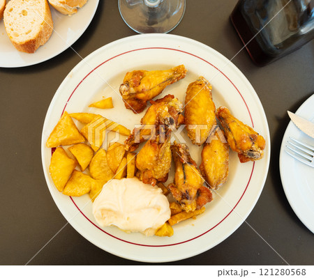 Roasted chicken wings french fries on a plate cooked in cafe Roasted chicken wings french fries on a plate cooked in cafe 121280568
