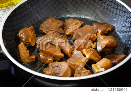 Chopped mushrooms are fried in black pan, cooking and kitchen concept 121280643