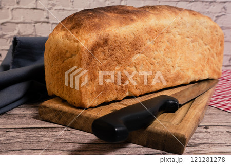 Piece of white bread on a cutting board with a knife. Piece of white bread on a cutting board with a knife. 121281278