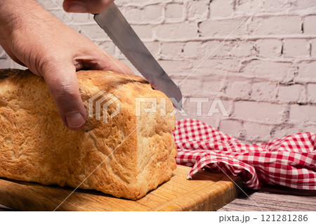 Hands cutting slices from a piece of white bread on a cutting board. Hands cutting slices from a piece of white bread on a cutting board. 121281286