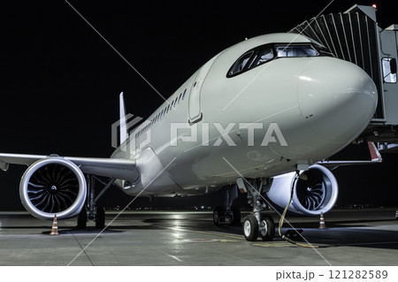 Close-up a white passenger aircraft at the jetway on an airport night apron 121282589