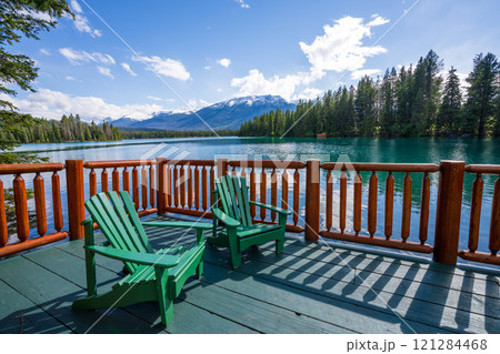 Jasper National Park summer landscape, Alberta, Canada. Adirondack chairs on lakeside of the Beauvert Lake (Lac Beauvert). Snowcapped Whistlers Peak mountain in the background. 121284468