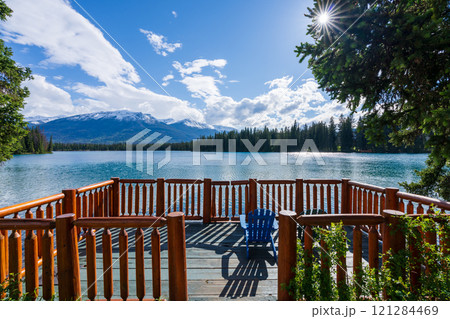 Jasper National Park summer landscape, Alberta, Canada. Adirondack chairs on lakeside of the Beauvert Lake (Lac Beauvert). Snowcapped Whistlers Peak mountain in the background. 121284469